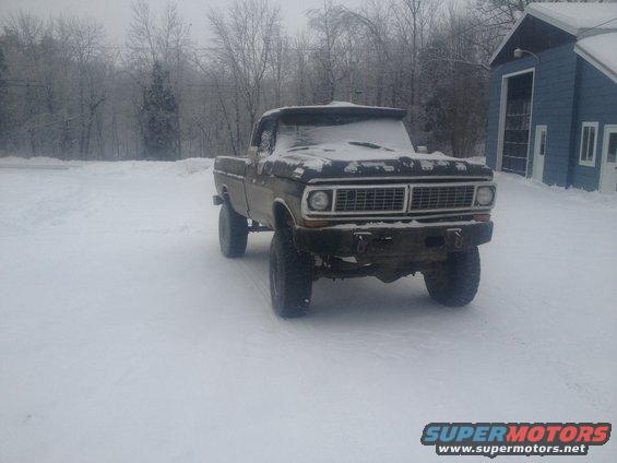 Ford F-250 pickup truck covered in snow, parked in a snowy yard next to a blue building