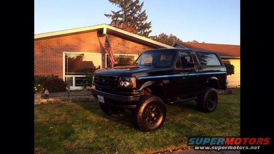 Black 1992 Ford Bronco with blue pinstripes parked in front of a brick house