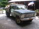 1979 Ford Bronco - 1967 Ford flatbed truck carrying a load of firewood in front of a wooden structure.