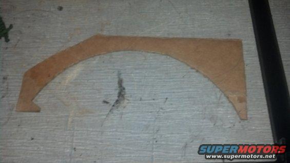 Cardboard cutout of a wheel arch on a gray surface
