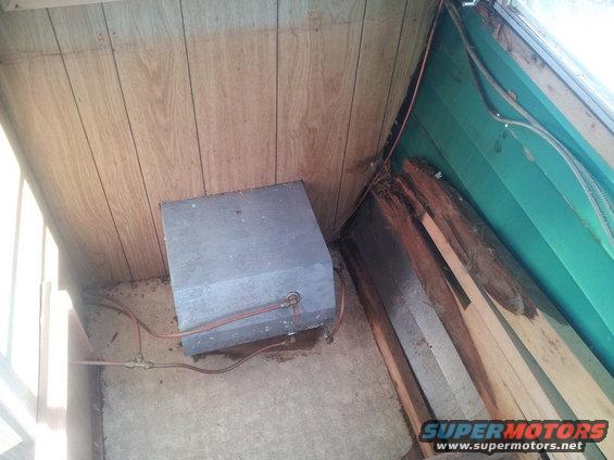 metal tank with copper pipes inside a room with wood paneling and green walls