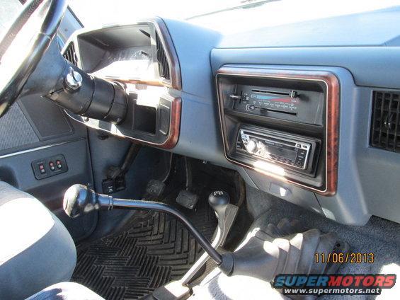 Truck interior with blue dashboard, aftermarket stereo, and floor shifter