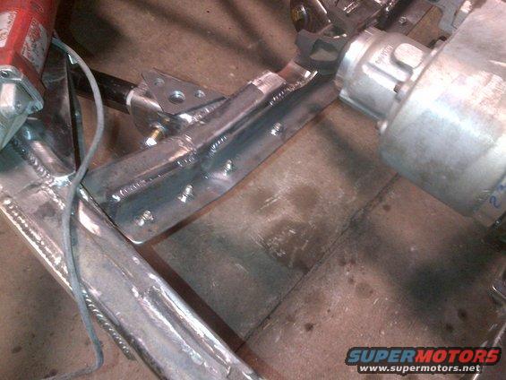Welded metal bracket attached to a vehicle frame, with a silver component on the right