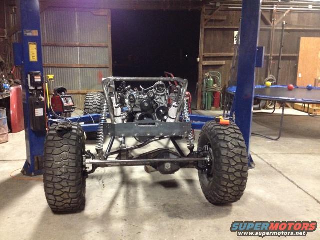 Jeep CJ7 chassis on lift, engine installed, large tires, custom suspension, rear view