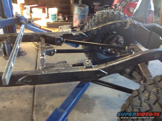 Jeep CJ frame on a lift, with suspension components and a tire visible