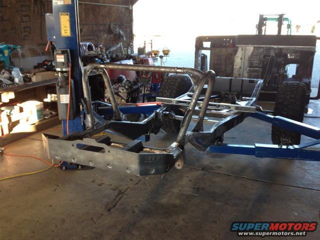 1985 Jeep CJ7 frame and roll cage assembly on a lift, with 'JEEP' visible on the front bumper