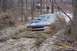 1978 Ford Bronco - An SUV is stuck deep in mud on a wooded trail, with another vehicle visible further back.