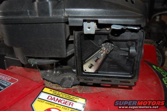 Close-up of lawn mower carburetor area with air filter cover removed