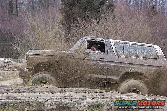 Mud-splattered 1978 Ford Bronco driving through a muddy terrain