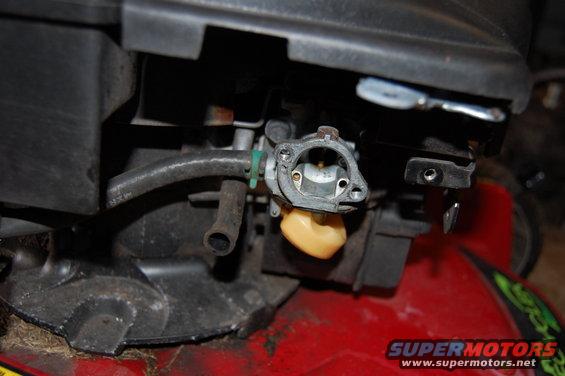 Close-up of a lawn mower carburetor with a yellow float