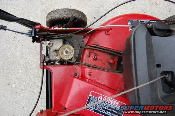 Red lawnmower engine and deck with a warning label and a SuperMotors.net watermark