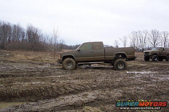 Muddy lifted pickup truck and SUV in a muddy field