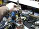 1998 Ford Crown Victoria - A mechanic uses a specialized tool to remove a part from a distributor assembly on a workbench.