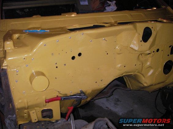 Yellow painted 1972 Ford Ranchero engine bay firewall with visible rivets and holes