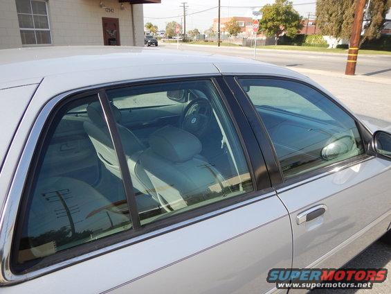 Side view of a silver sedan, showing the interior seats and dashboard. A 'SUPERMOTORS' watermark is visible