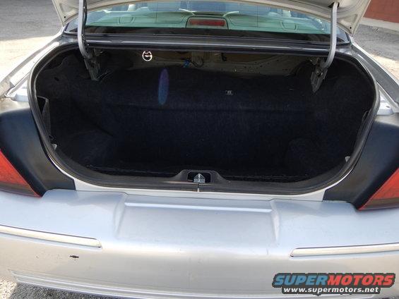 Open trunk of a silver sedan. The trunk is lined with black carpet
