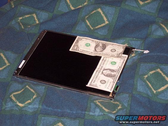 Car stereo screen with two dollar bills on top, on a patterned blanket