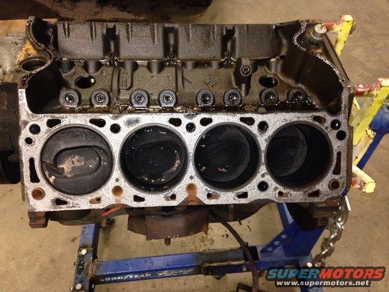 Engine block with four cylinders visible, on an engine stand