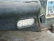 2000 Ford F-250 - Close-up of a worn rear bumper assembly, showing a trailer light and license plate.