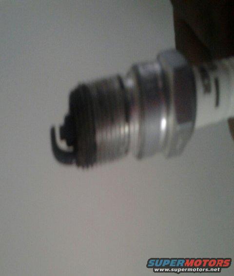 Close-up of a used spark plug with visible wear on the electrode