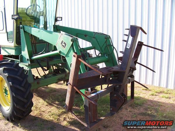 Tractor side view with green loader and hay forks attached