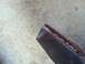 1977 Ford F-350 - A rusted metal part rests on a concrete floor, with a Supermotors.net logo in the corner.