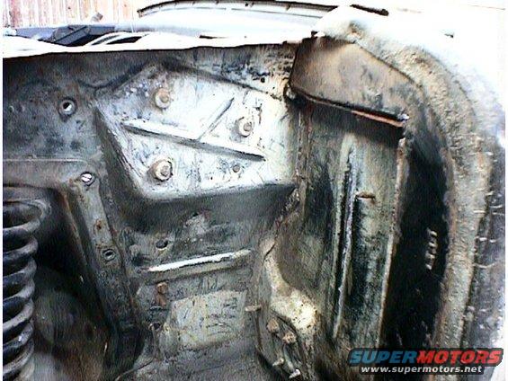 Close-up of a rusty, weathered engine bay structure with visible bolts and metal bracing