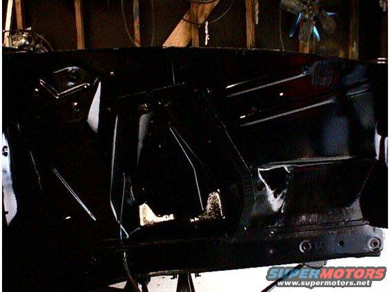 Black car chassis with visible rust and damage, viewed from the side