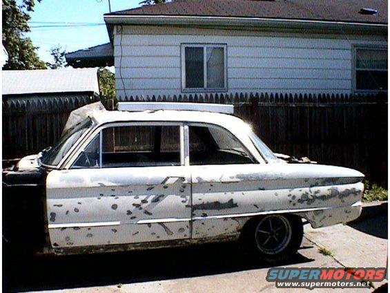 White 1960 Ford Falcon sedan, side view, showing peeling paint and damage