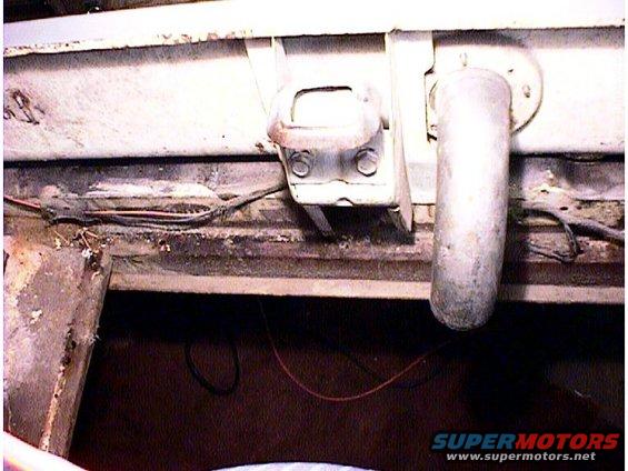 Undercarriage of a vehicle showing a rusty metal frame, exhaust pipe, and wiring