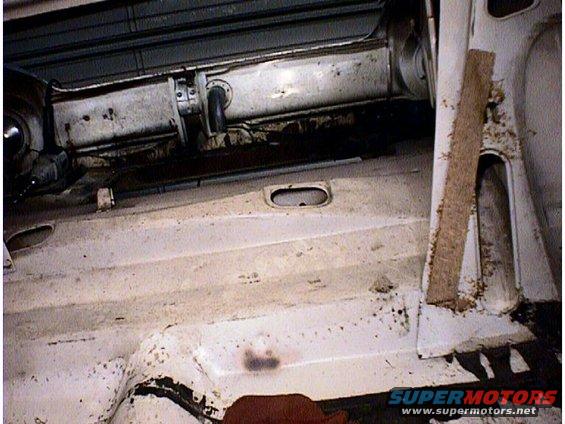 Interior of a dirty white car, showing floor and side panel