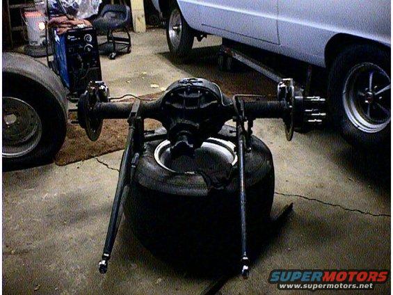 Rear axle assembly on a tire, with a white car in the background