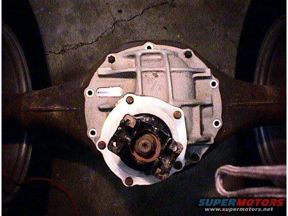 Close-up of a rear differential assembly with a white label on the housing. A driveshaft yoke is attached