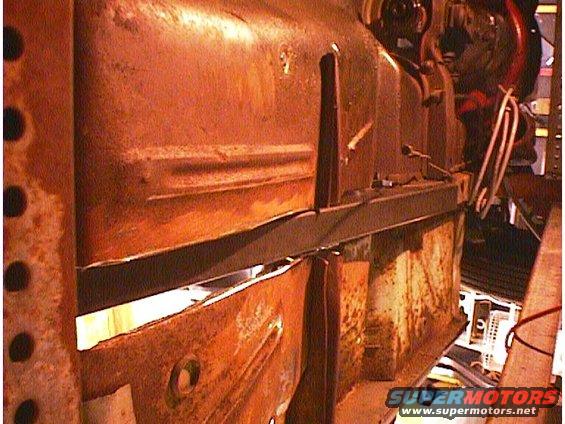 Rusty car frame section with visible structural supports and some wiring