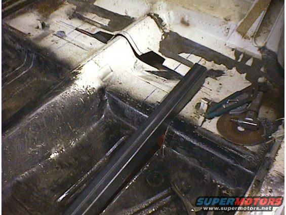Interior floor pan of a car undergoing repair, showing metalwork and tools