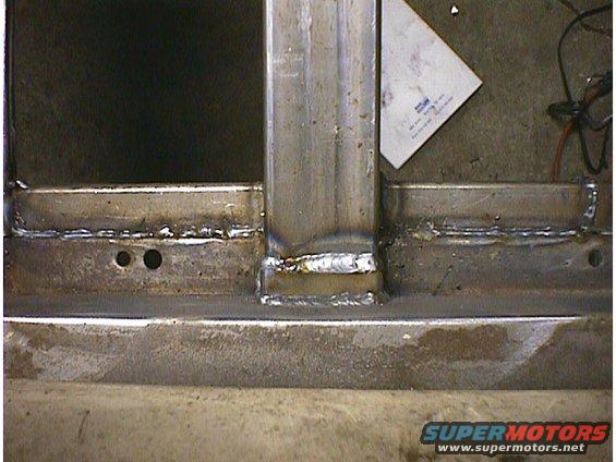Close-up of welded metal frame sections with a piece of paper on the right