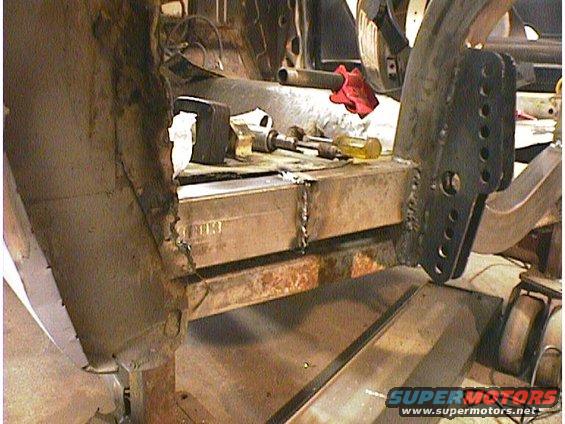Close-up of a car's frame undergoing repair with tools on a metal beam