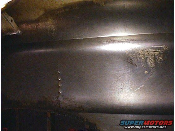 Underside of a car, showing metal panels and some rust. Supermotors.net logo visible