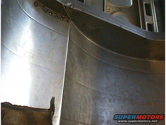 Close-up of a silver metal panel with visible welds and curved sections, likely from a car's interior or undercarriage