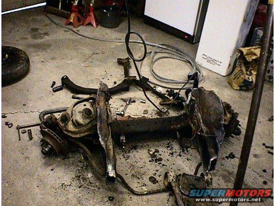 Disassembled vehicle subframe with suspension components on a concrete floor