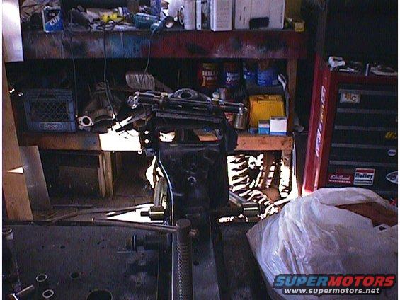 Engine block and frame assembly on a workbench in a cluttered garage