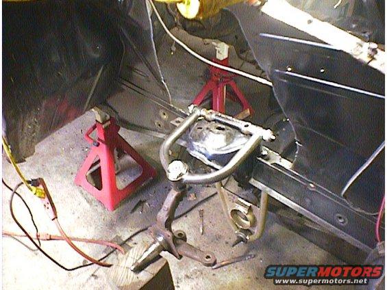 Car suspension assembly on jack stands, showing control arm and spindle