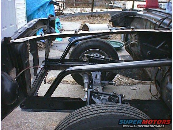 Car frame and suspension system with wheels visible. The body is mostly removed