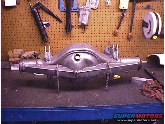 Rear axle housing with fabricated brackets, resting on a workbench