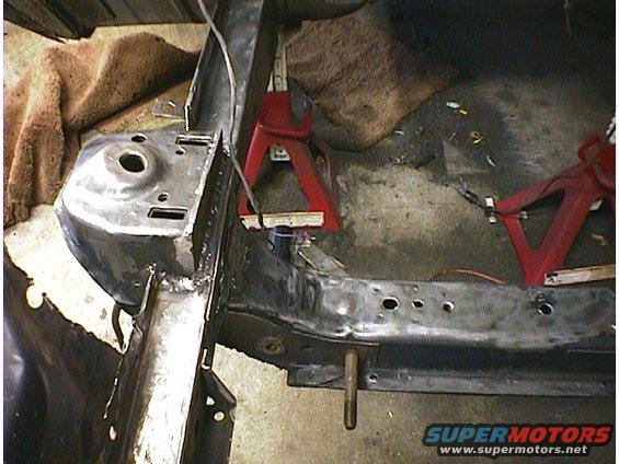 Car frame on red jack stands, showing suspension mounting points