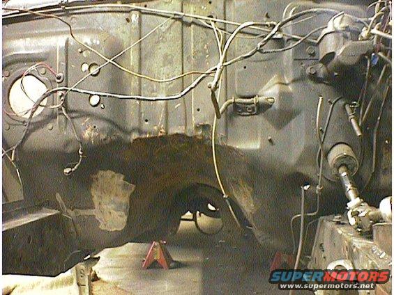 Engine bay firewall with wiring, steering column visible. Rusty section on firewall