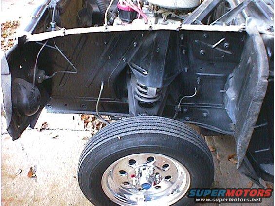 Front wheel and engine bay of a car, appears to be undergoing restoration