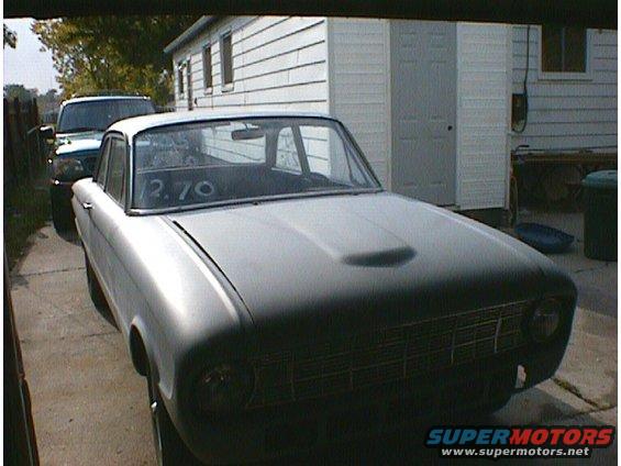 Gray 1960 Ford Falcon with a scoop on the hood, parked next to a dark SUV
