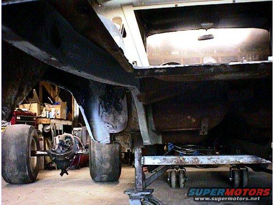 Car frame and rear axle on stands, interior visible