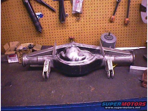 Rear axle assembly with welded brackets and a central differential housing, resting on a workbench